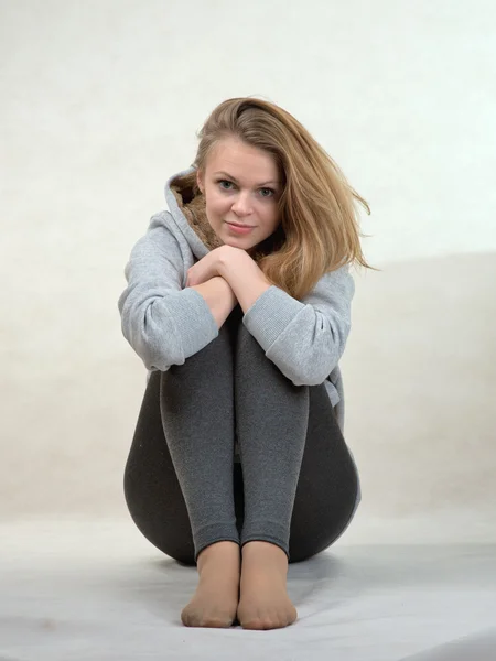 Příjemná dívka sedí s sepjatýma rukama kolena — Stock fotografie