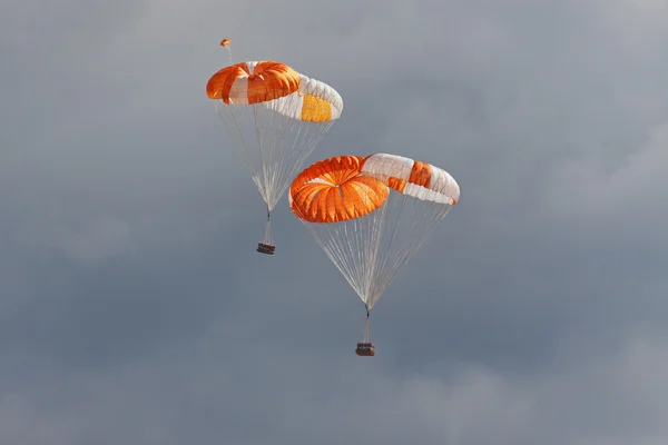 Freights on parachutes go down the earth — Stock Photo, Image