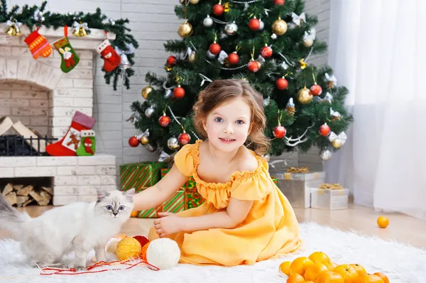 Bambina con un gatto in una stanza per le vacanze — Foto Stock