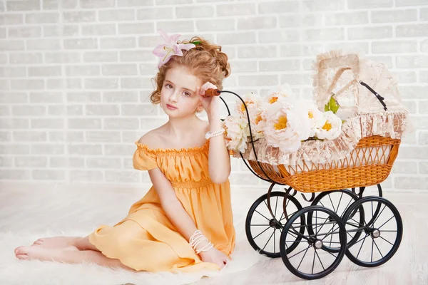 Κορίτσι σε πορτοκαλί φόρεμα με vintage καροτσάκι — Φωτογραφία Αρχείου