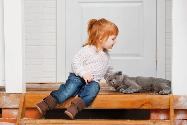 Kleines Mädchen mit einer Katze auf einer Veranda — Stockfoto