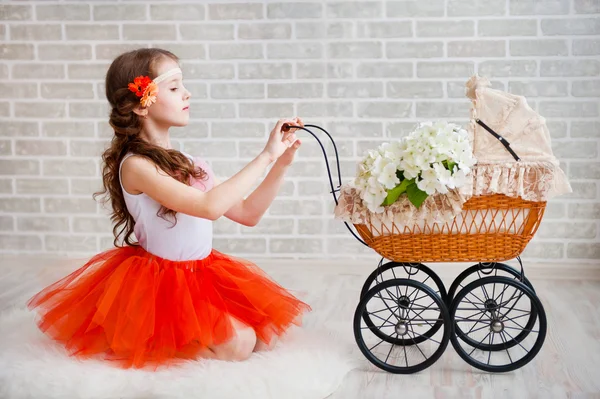 Girl in orange skirt with vintage pram — Stock Photo, Image