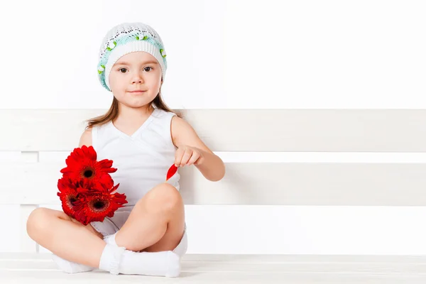 Chica con flores sentado en el banco — Foto de Stock