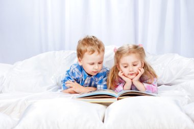 küçük kız ve erkek yatakta kitap okumak