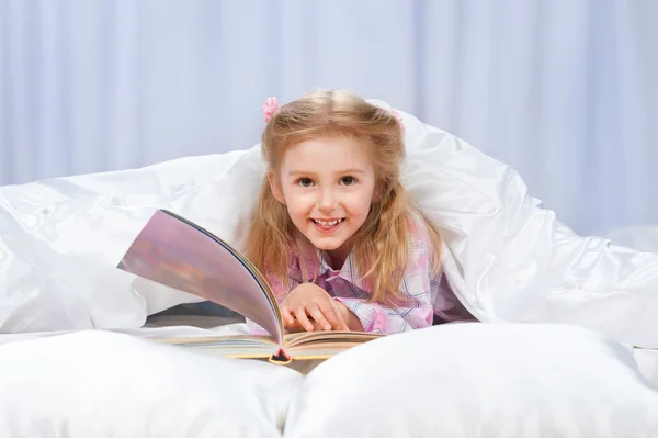La niña leyó el libro en la cama. — Foto de Stock