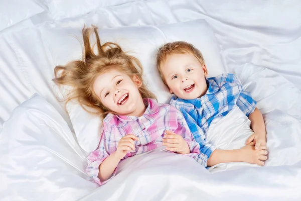 Glücklicher kleiner Junge und Mädchen im Bett — Stockfoto