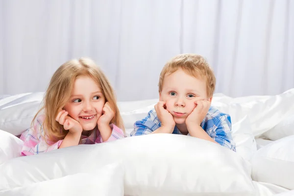 Zwei fröhliche Kinder spielen auf dem Bett — Stockfoto