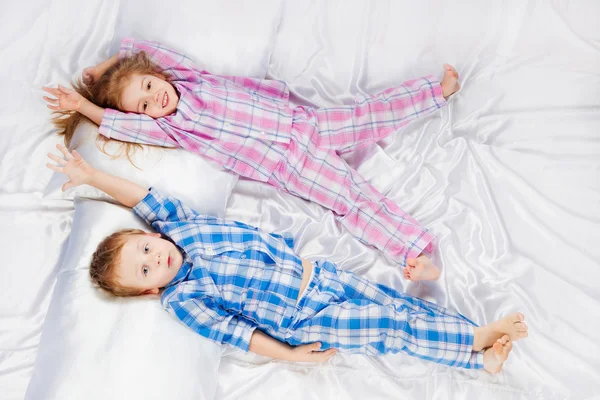 Duas crianças alegres brincando na cama — Fotografia de Stock