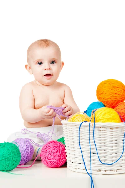 Bébé souriant joue avec des boules colorées de fil — Photo