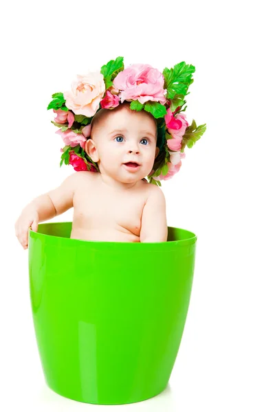 Baby in a wreath sits in a flower pot — Stock Photo, Image