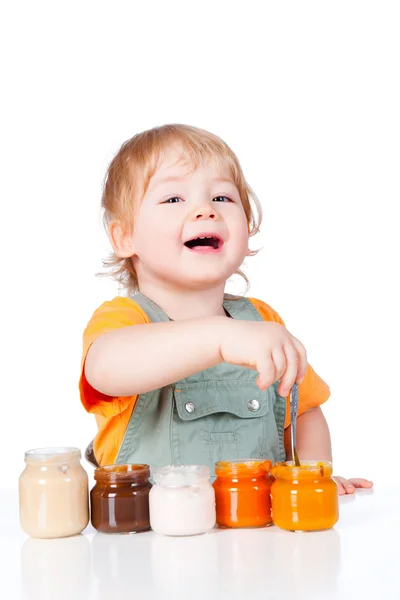 Menino com pequenos frascos de comida de bebê — Fotografia de Stock