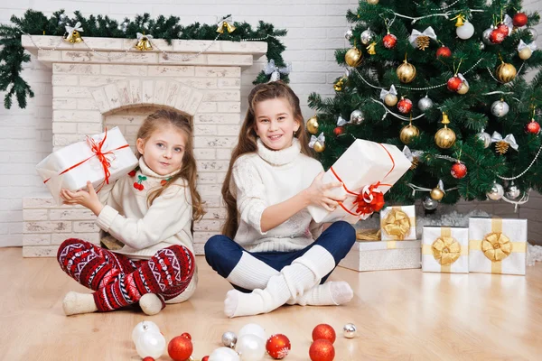 Zwei kleine Mädchen in einem Raum mit Weihnachtsgeschenken — Stockfoto