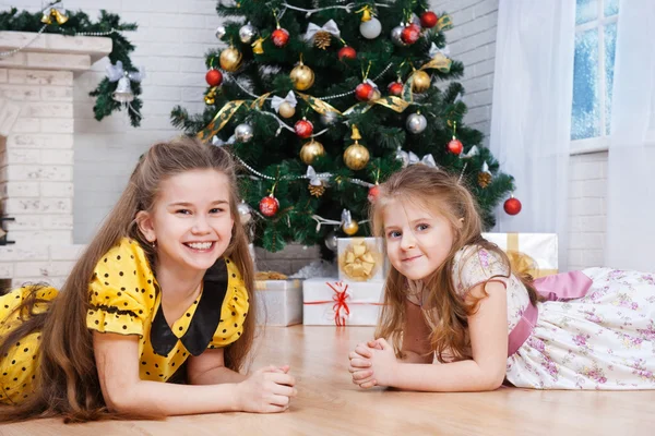 Dos niñas pequeñas cerca del árbol de Navidad con regalos — Foto de Stock