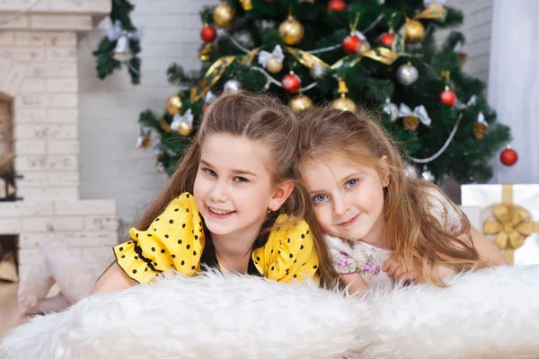 Dos niñas pequeñas cerca del árbol de Navidad con regalos —  Fotos de Stock