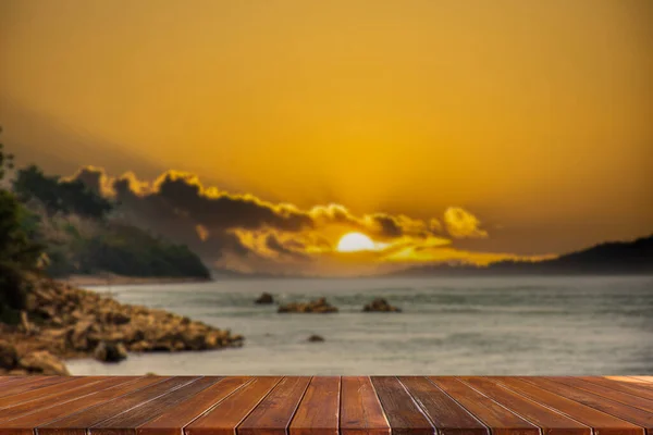 Empty wooden table against blurred river background and sunset