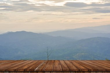 Wooden table and blur of beauty, sunset sky, and mountains as background.