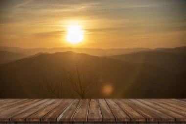 Wooden table and blur of beauty, sunset sky, and mountains as background.