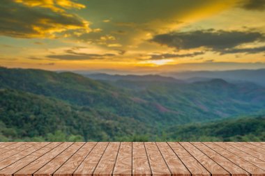 Wooden table and blur of beauty, sunset sky, and mountains as background.