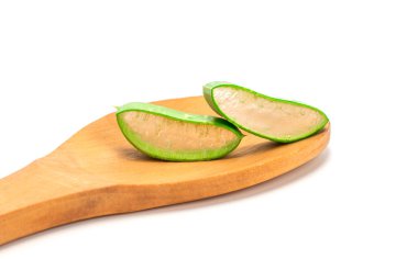 Beyaz arka planda izole edilmiş ahşap kaşıkta dilimlenmiş taze yeşil aloe yaprakları. Cilt bakımı konsepti sağlık ve güzellik merkezi