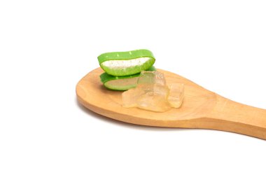 Beyaz arka planda izole edilmiş ahşap kaşıkta dilimlenmiş taze yeşil aloe yaprakları. Cilt bakımı, sağlık ve güzellik merkezi