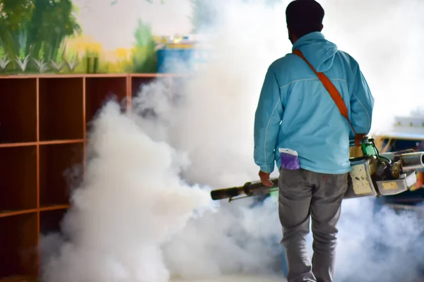 Workers spray mosquito pesticides with a motorized sprayer