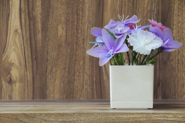 Tahta bir masanın üzerine yerleştirilmiş vazodaki sahte çiçekler, ahşap tahıl mahsulü arka plan tasarımı için fotokopi alanı..