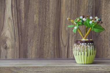 Tahta bir masanın üzerine yerleştirilmiş vazodaki sahte çiçekler, ahşap tahıl mahsulü arka plan tasarımı için fotokopi alanı..