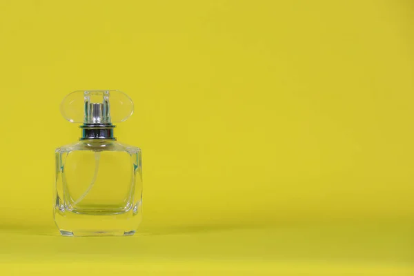 perfume bottle laid on a yellow background with copy space for design