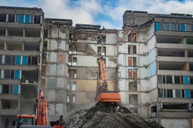 Bir kazıcıyla binayı sökmek. Eski bir binanın yıkımı..