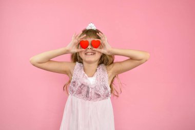 Pembe arka planda neşeli poz veren kız.