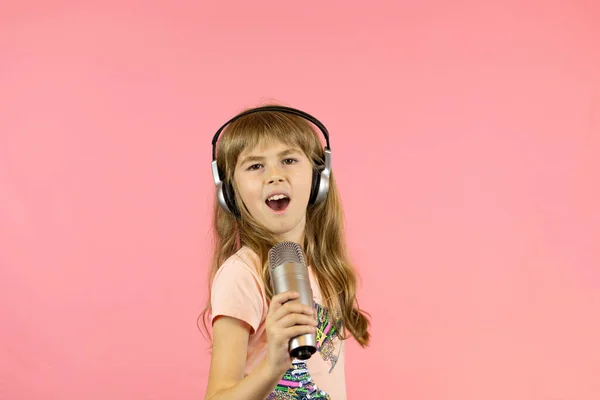 Pequeña chica alegre canta en el micrófono. — Foto de Stock