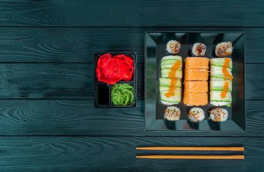 Siyah bir tabakta lezzetli suşi, siyah bir tahta üzerinde uzanır.