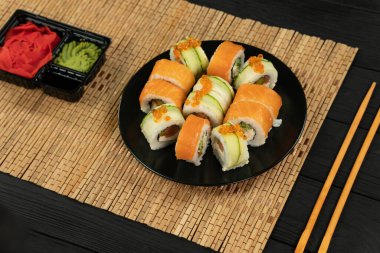 Siyah ahşap arka planda somonlu suşi rulosu. Japon mutfağı .