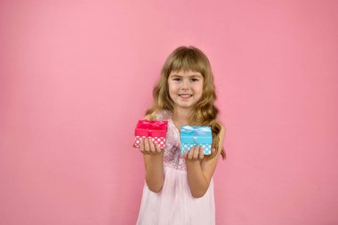 Pembe arka planda neşeli poz veren bir kız. Elinde hediyeyle pembe elbiseli küçük bir kız. Mutlu yıllar kızım..