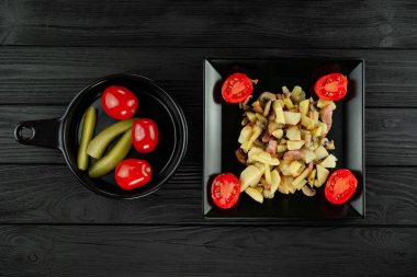 Siyah ahşap arka planda domatesli patates kızartması ve ıspanak yaprakları..