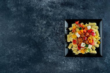 Sebzeli makarna, kuşkonmaz, bezelye, dolmalık biber, domates, sos, siyah arkaplanda mozzarella peyniri. Sebzeli İtalyan makarnası ve koyu bir arka planda baharat. Anlaşıldı..