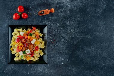 Sebzeli makarna, kuşkonmaz, bezelye, dolmalık biber, domates, sos, siyah arkaplanda mozzarella peyniri. Sebzeli İtalyan makarnası ve koyu bir arka planda baharat. Anlaşıldı..