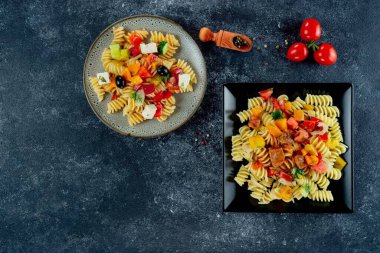 Sebzeli makarna, kuşkonmaz, bezelye, dolmalık biber, domates, sos, siyah arkaplanda mozzarella peyniri. Sebzeli İtalyan makarnası ve koyu bir arka planda baharat. Anlaşıldı..