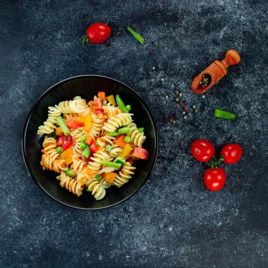 Sebzeli makarna, kuşkonmaz, bezelye, dolmalık biber, domates, sos, siyah arkaplanda mozzarella peyniri. Sebzeli İtalyan makarnası ve koyu bir arka planda baharat. Anlaşıldı..