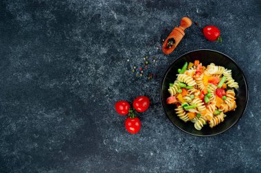 Sebzeli makarna, kuşkonmaz, bezelye, dolmalık biber, domates, sos, siyah arkaplanda mozzarella peyniri. Sebzeli İtalyan makarnası ve koyu bir arka planda baharat. Anlaşıldı..