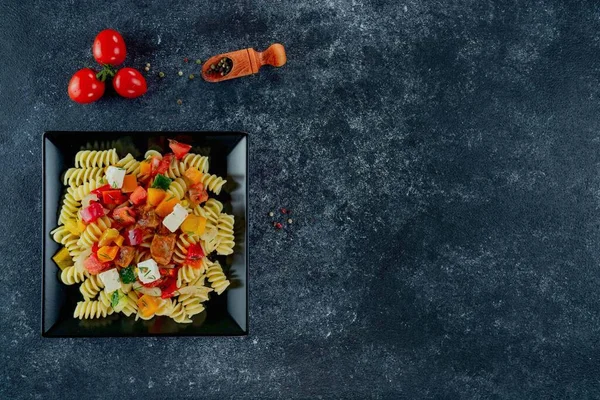 Sebzeli makarna, kuşkonmaz, bezelye, dolmalık biber, domates, sos, siyah arkaplanda mozzarella peyniri. Sebzeli İtalyan makarnası ve koyu bir arka planda baharat. Anlaşıldı..