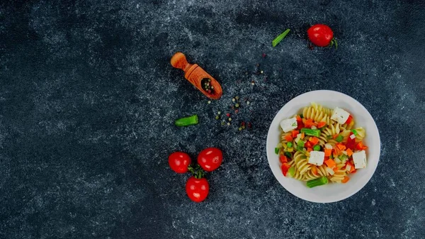 Sebzeli makarna, kuşkonmaz, bezelye, dolmalık biber, domates, sos, siyah arkaplanda mozzarella peyniri. Sebzeli İtalyan makarnası ve koyu bir arka planda baharat. Anlaşıldı..