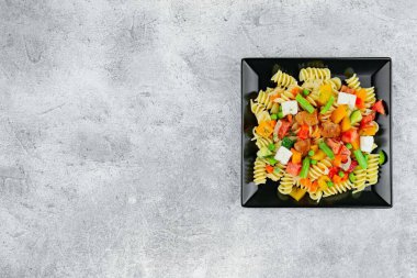 Sebzeli makarna, sos, arka planda hafif desenli mozzarella peyniri. Siyah arka planda sebzeli ve baharatlı İtalyan makarnası. Uzayı kopyala Düz Düzen.