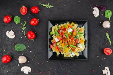 Sebzeli makarna, kuşkonmaz, bezelye, dolmalık biber, domates, sos, siyah arkaplanda mozzarella peyniri. Sebzeli İtalyan makarnası ve koyu bir arka planda baharat. Anlaşıldı..