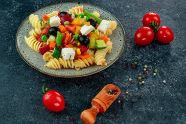 Sebzeli makarna, kuşkonmaz, bezelye, dolmalık biber, domates, sos, siyah arkaplanda mozzarella peyniri. Sebzeli İtalyan makarnası ve arka planda baharat..