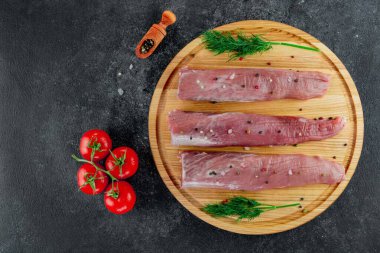 Siyah arka planda domuz filetosu ve sebze ve dereotlu pansiyon. Kesme tahtasında et filetosu.