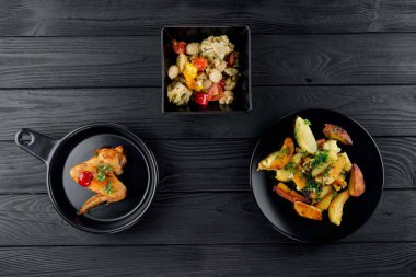 Mantarlı kızarmış patates ve baharatlı siyah arka planda domates. Sebzeli lezzetli patates ve siyah panoda kızarmış tavuk. Sebze ve patatesli kızarmış tavuk..