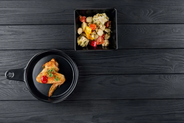 Mantarlı kızarmış patates ve baharatlı siyah arka planda domates. Sebzeli lezzetli patates ve siyah panoda kızarmış tavuk. Sebze ve patatesli kızarmış tavuk..