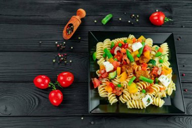 Sebzeli İtalyan makarnası ve koyu arkaplanda baharat..