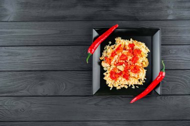 Geleneksel Asya yemeği - pirinç pilavı, sebze ve et siyah arka planda bir tabakta. Asya yemekleri. Yukarıdan görüntüle.